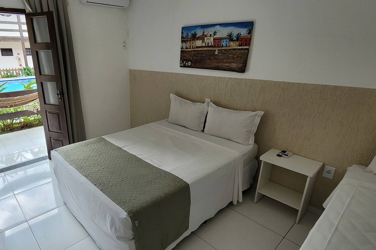 Una habitación de hotel con una cama, una mesita de noche y un cuadro en la pared.