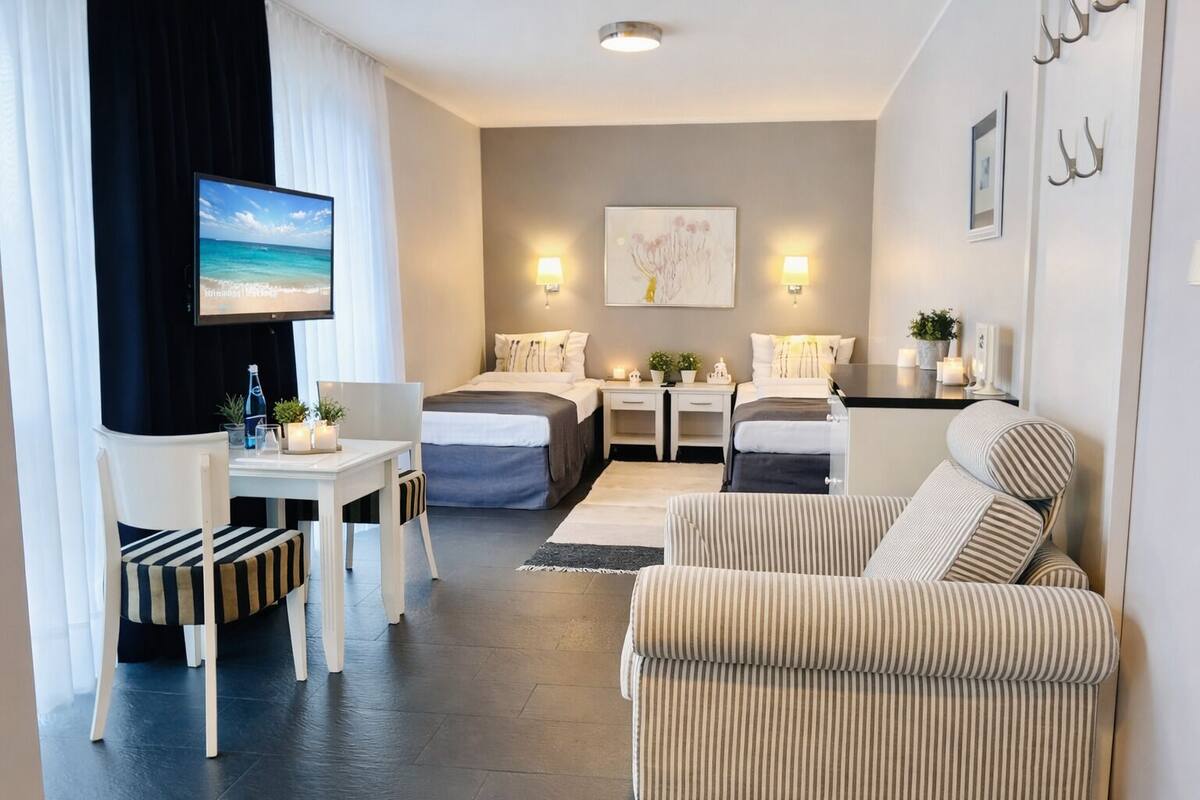 A modern hotel room with a bed, a sofa, a desk, and a TV.