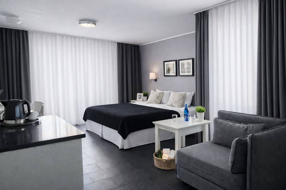 A modern hotel room with a bed, a desk, a chair, and a coffee maker.