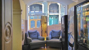 A lobby with two grey armchairs, a decorative pillar, and a vending machine.