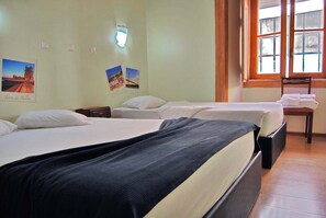 A hotel room with two beds, a nightstand, a chair, and a window with a view. - 161 Norte Guesthouse (Lisbon)