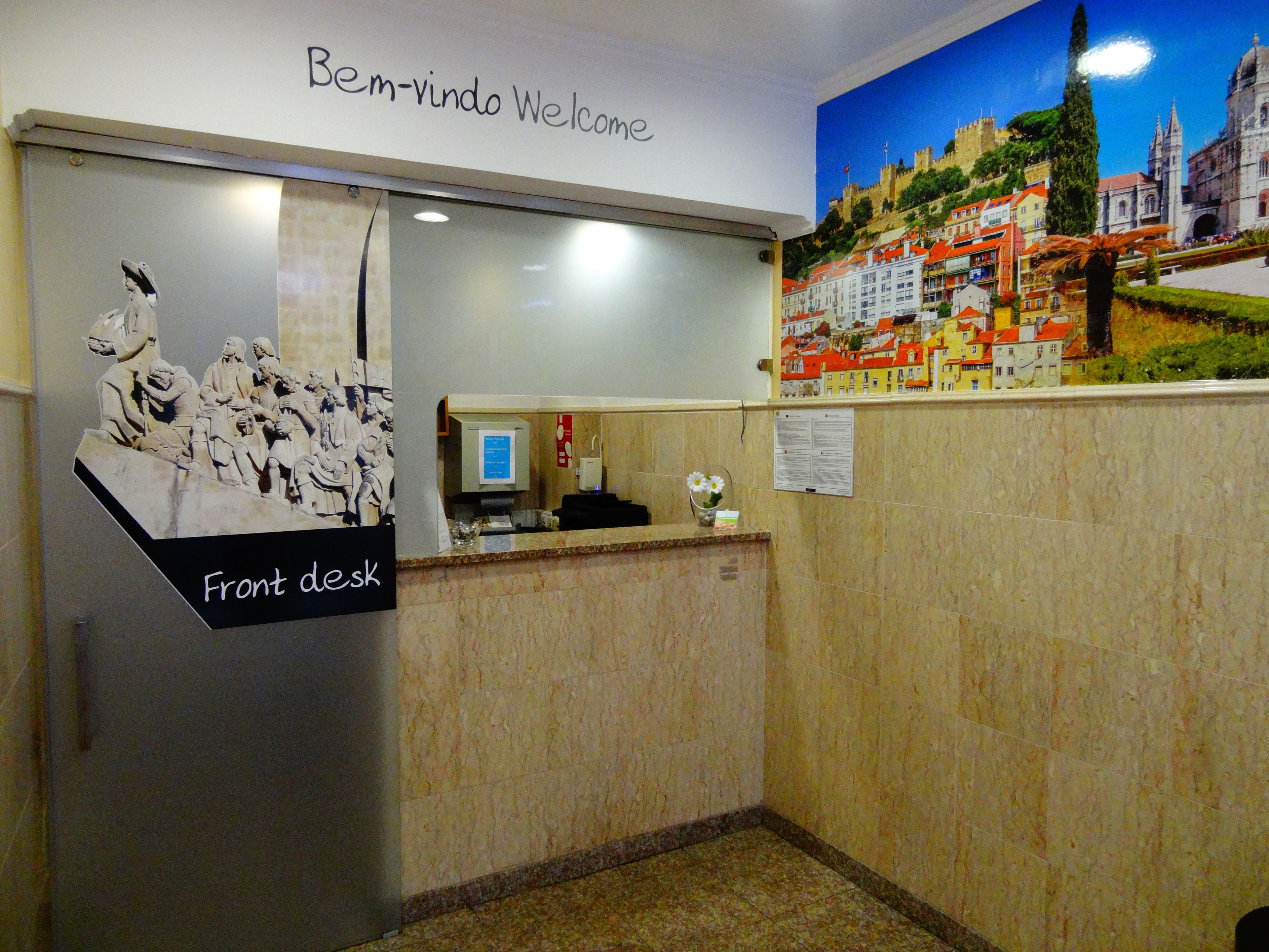 A reception desk with a welcome sign, a computer, and a bulletin board.