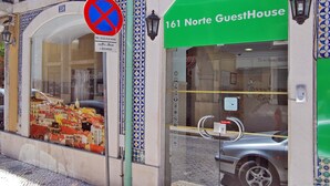 A building with a green sign reading "161 Norte GuestHouse" and a no parking sign.