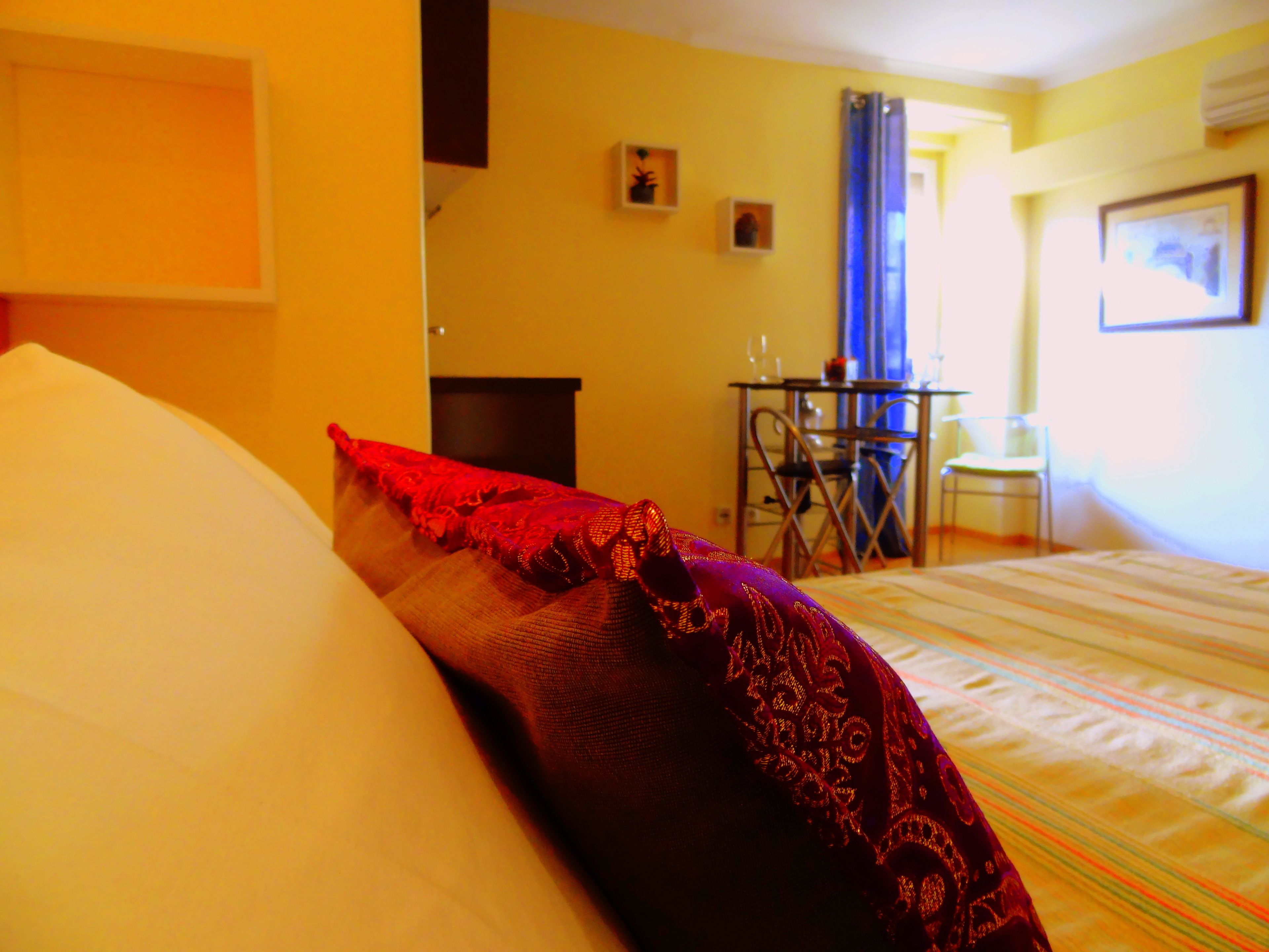Een hotelkamer met een bed, een tafeltje met stoelen en een raam met gordijnen.