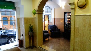 A lobby with a marble floor, a green plant, a seating area with chairs, and a hat on the wall.