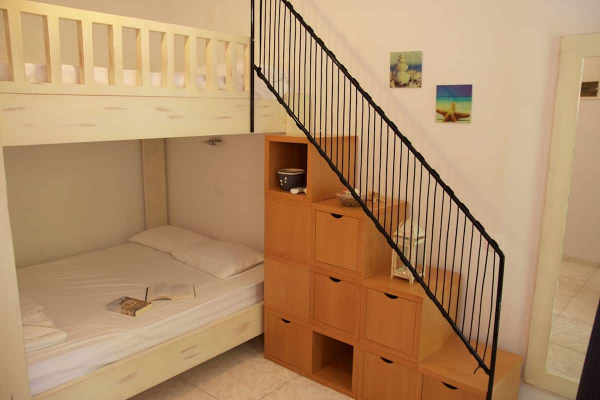 A bunk bed with a wooden ladder and a small wooden cabinet below.