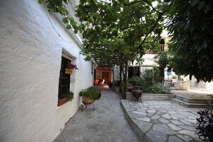Un patio estrecho con pared blanca, un camino de piedra y plantas en macetas.