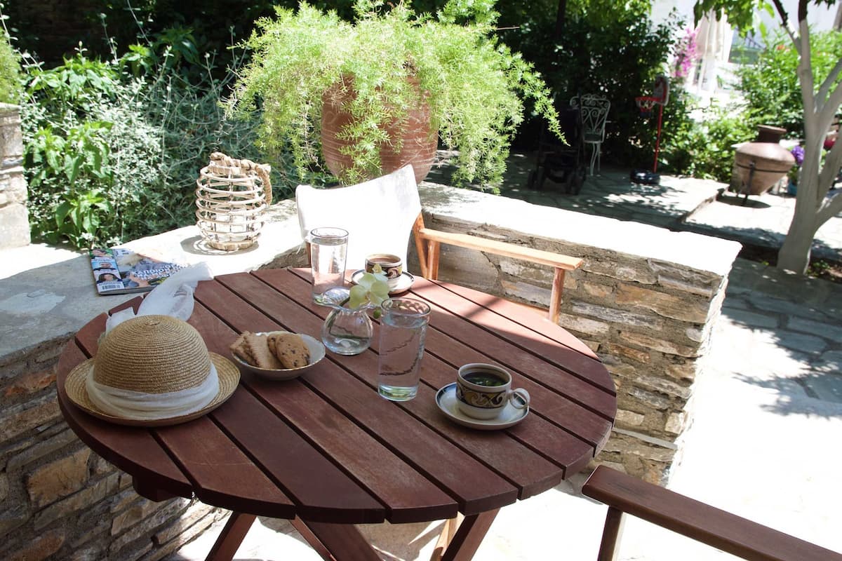 A wooden table with a hat, a glass of water, a cup of coffee, and a plate of cookies.