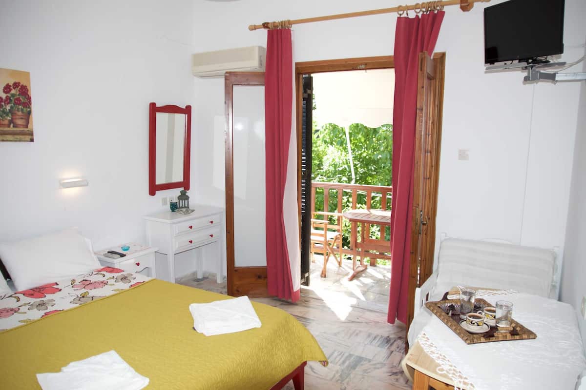 A bedroom with a bed, a bedside table, a mirror, and a balcony with a table and chairs.