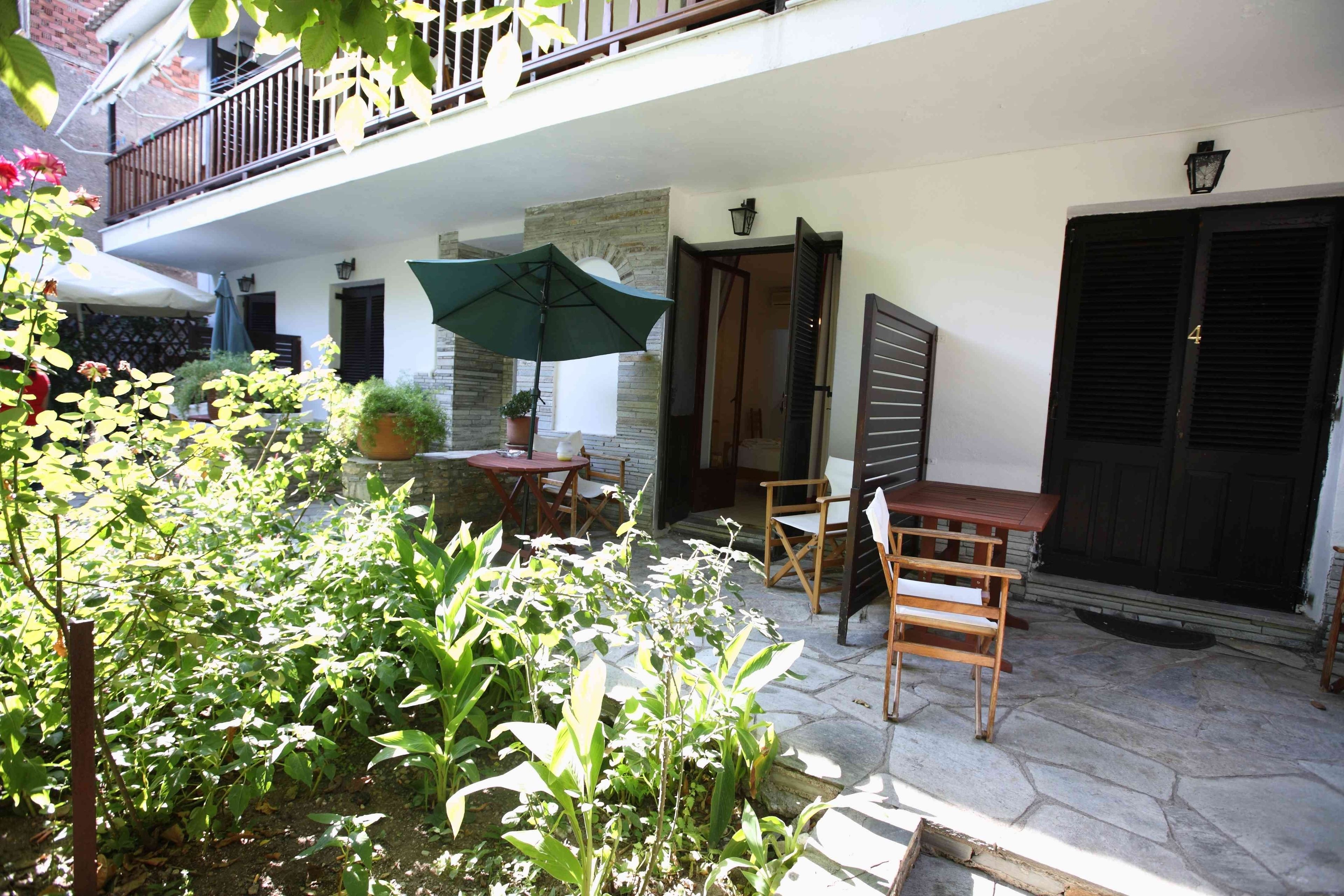 Un patio con una mesa, sillas, una planta en maceta y una puerta.