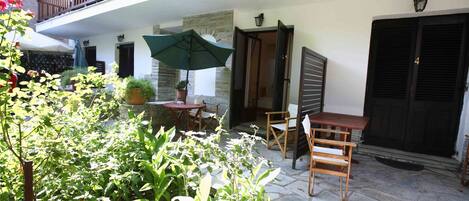 Un patio con una mesa, sillas, una planta en maceta y una puerta.