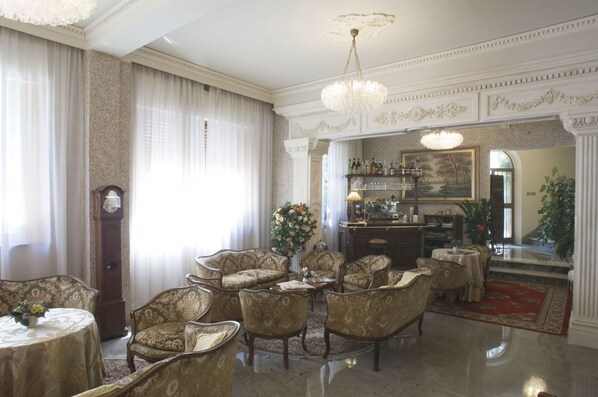 Uma sala de jantar formal com um candelabro, um relógio e um espaço de bar com um quadro.