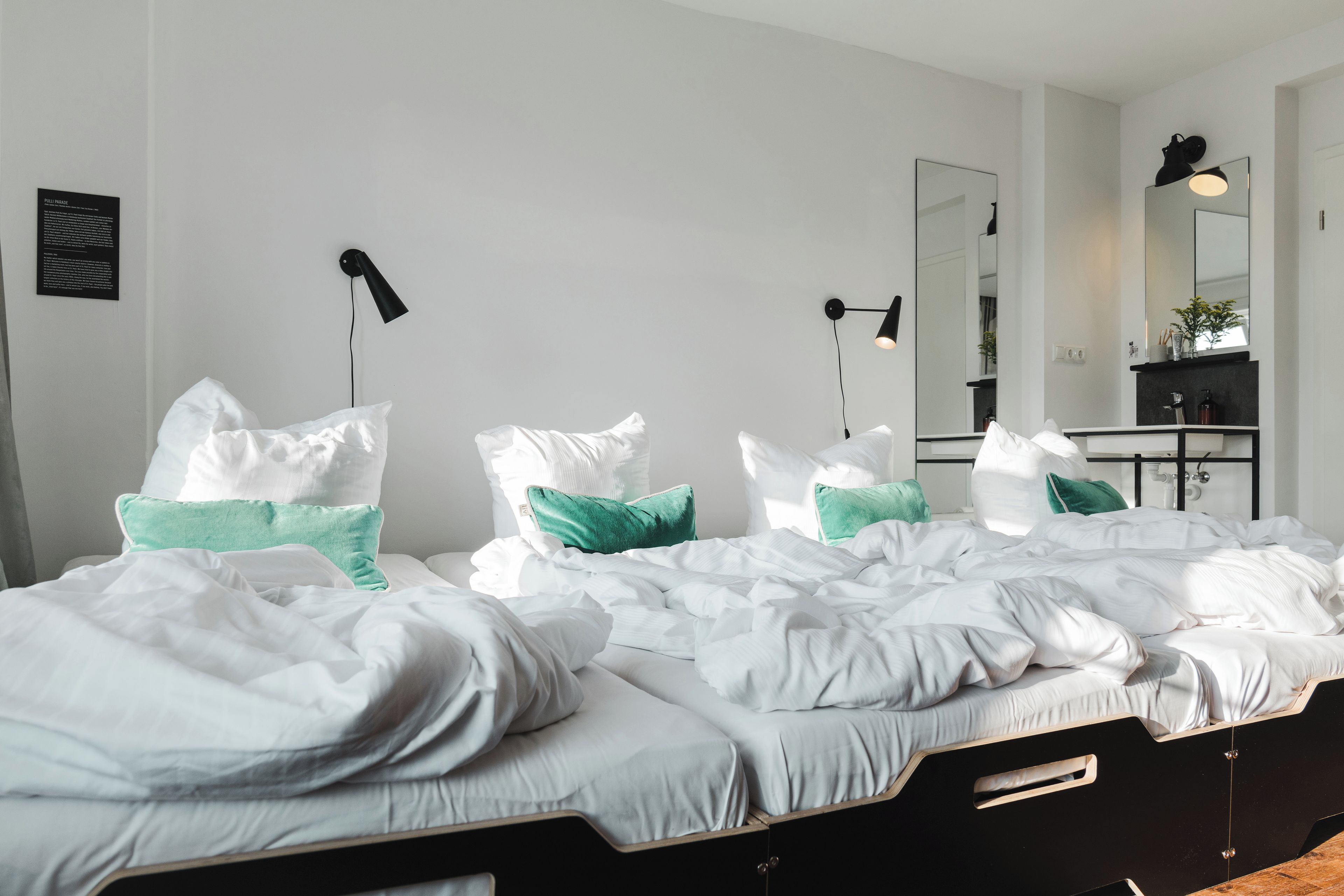 Een hotelkamer met een groot bed, twee nachtkastjes, een spiegel en een wandlamp.