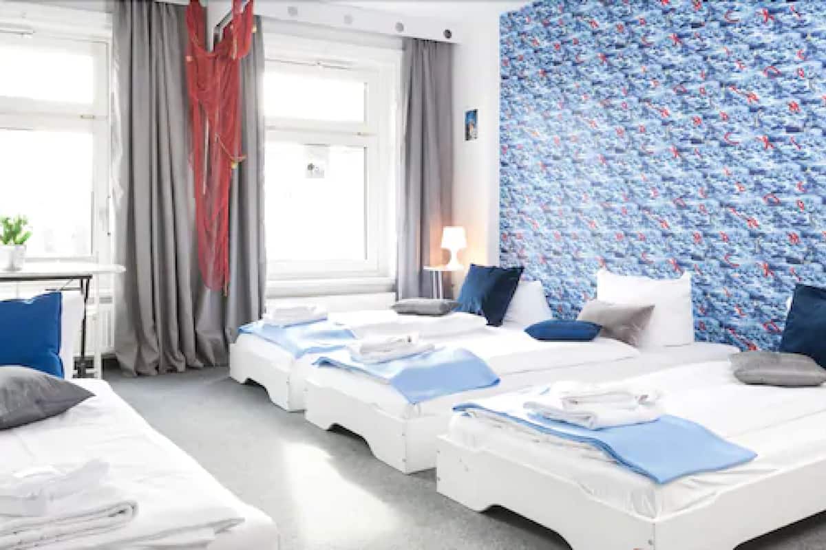 A hotel room with two beds, a desk, a lamp, and a window with curtains.