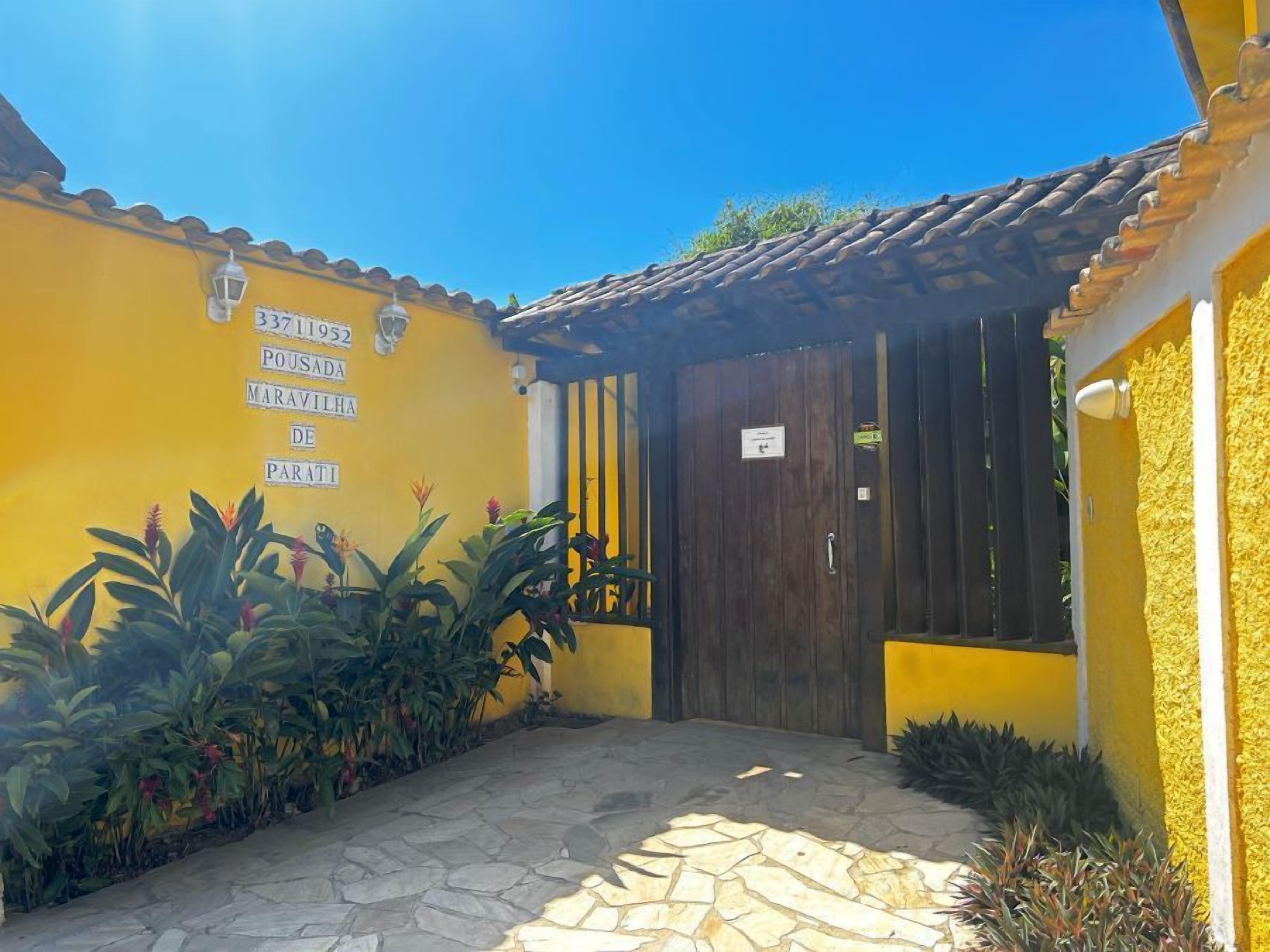 A yellow building with a tiled roof, a dark wooden door, and a stone-paved entrance.