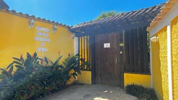 A yellow building with a tiled roof, a dark wooden door, and a stone-paved entrance.