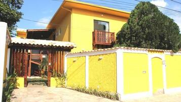 Un edificio amarillo con balcón, escalera y entrada protegida por una reja.