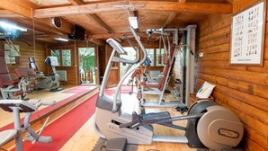 Uma academia com diversos equipamentos de exercício, incluindo uma máquina de remo e aparelhos de musculação.