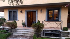 Uma casa com um caminho de pedra que leva à entrada, uma porta e duas janelas com persianas.