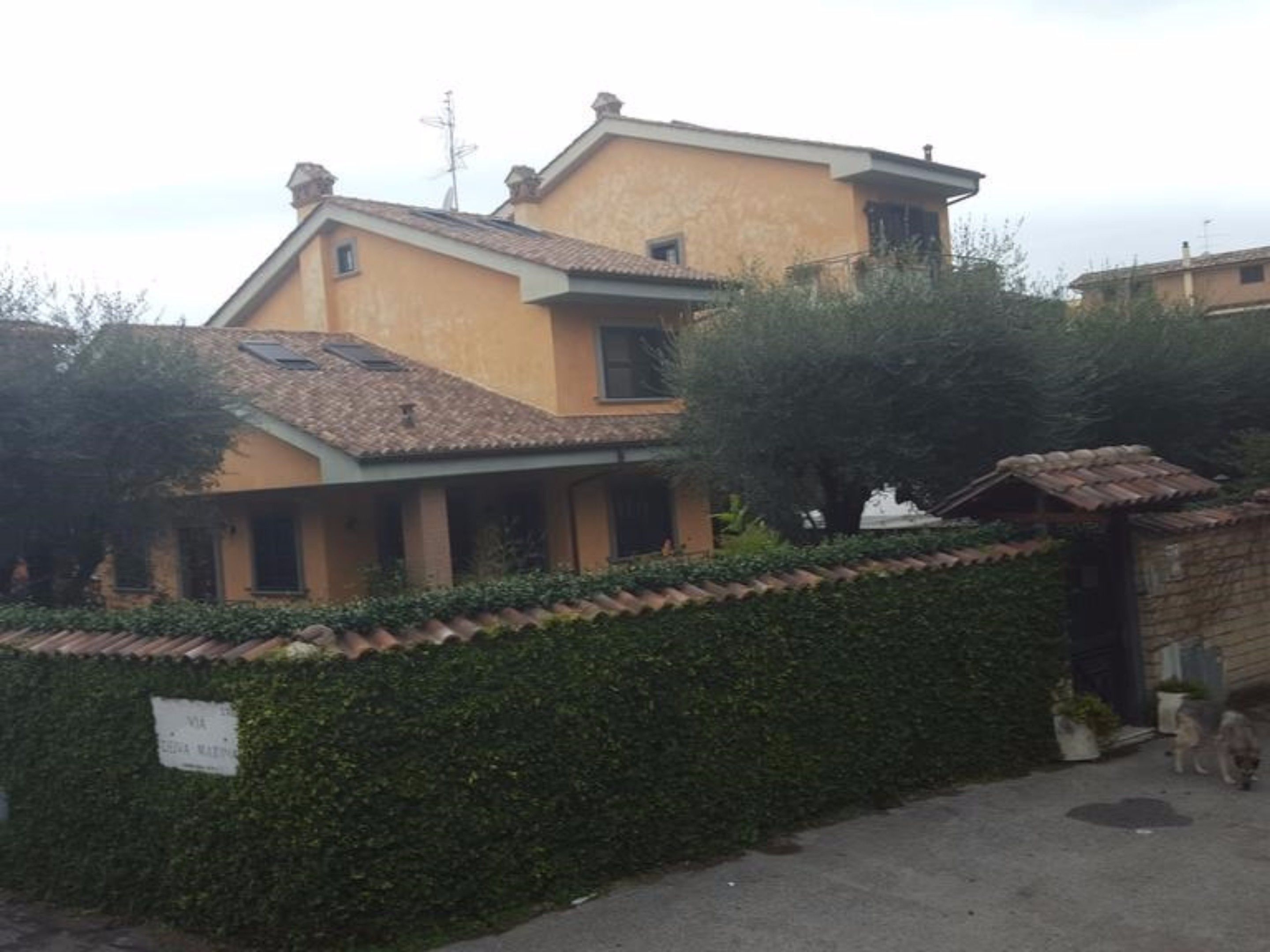 A two-story house with a tiled roof and a small attached structure.
