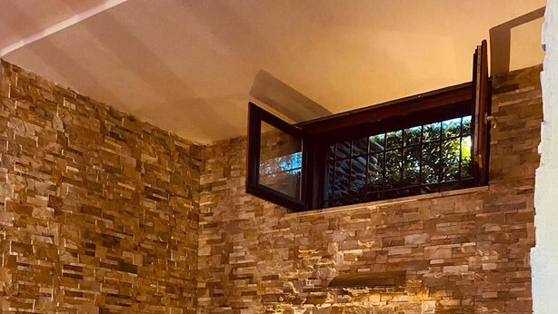 Uma área de spa com parede de pedra, uma pequena piscina e pétalas de rosas no chão.