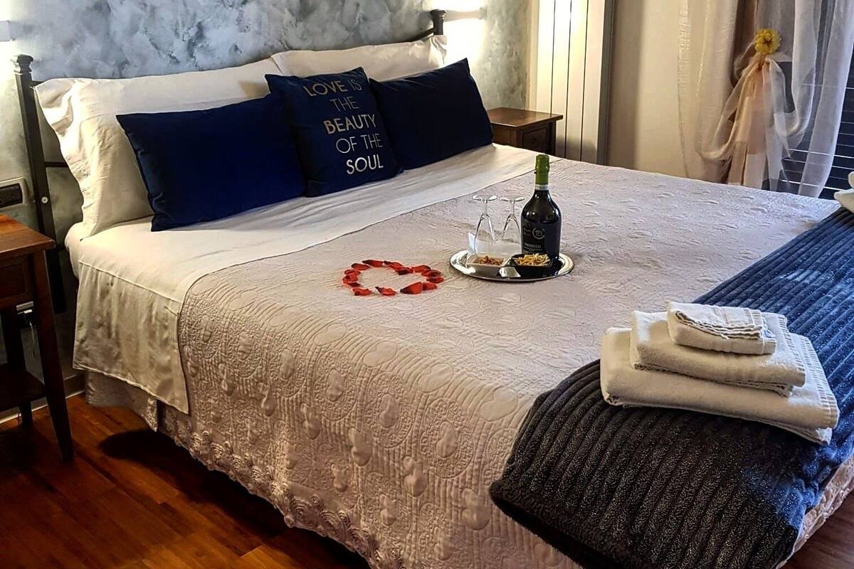 Un lit bien fait, agrémenté d’une décoration en forme de cœur, une bouteille de vin et un plateau avec des amuse-gueules.