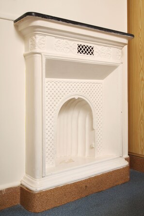 A white fireplace with intricate carvings and a black mantel. - Hôtel Marignan (Paris)