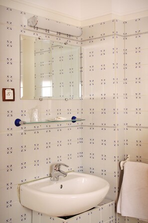 A bathroom with a white sink, a mirror, and a towel rack. - Hôtel Marignan (Paris)