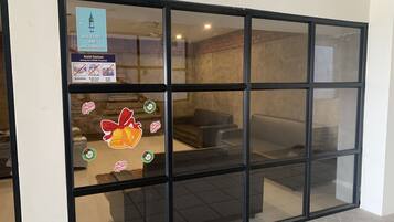 A hotel reception area with a glass door, a sign indicating vaccination status, and holiday decorations.
