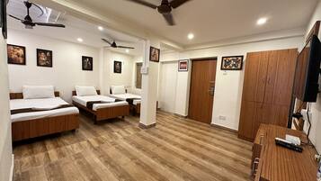 A hotel room with two single beds, a wooden desk, a TV, and ceiling fans.