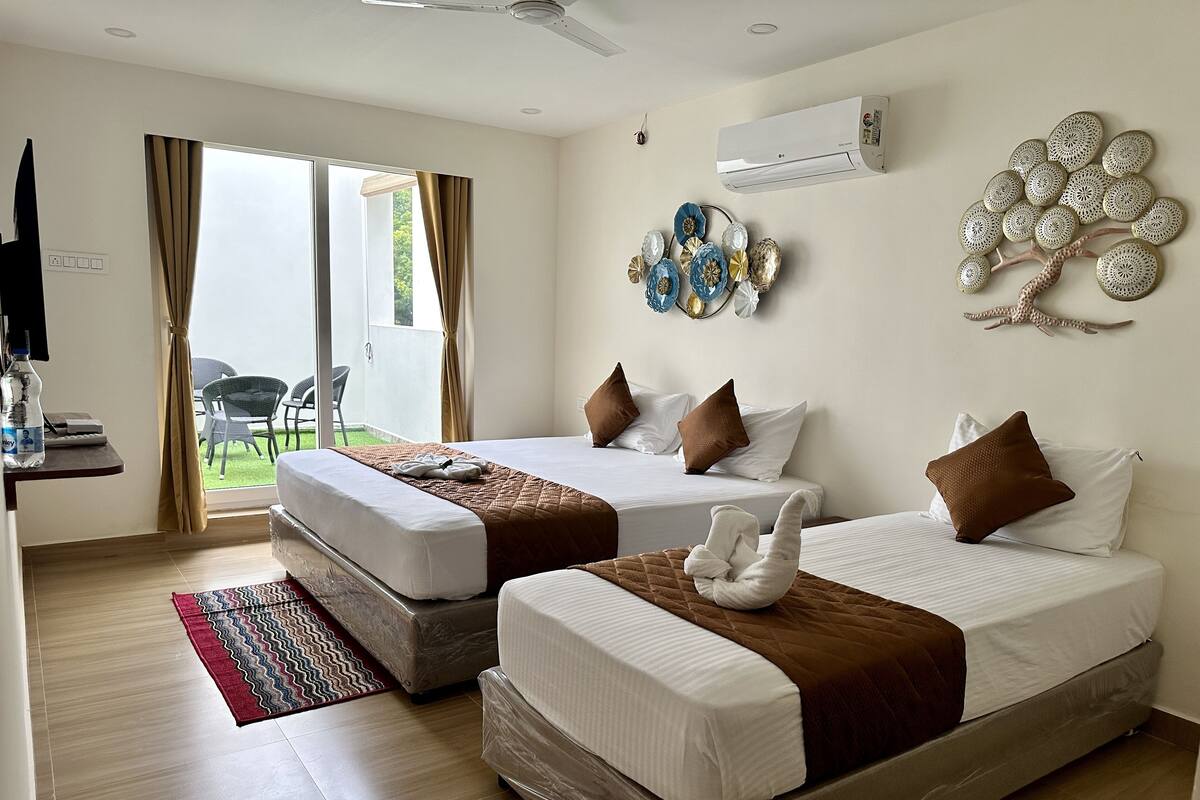 A hotel room with two beds, a desk with a chair, an air conditioner, and a decorative wall piece.