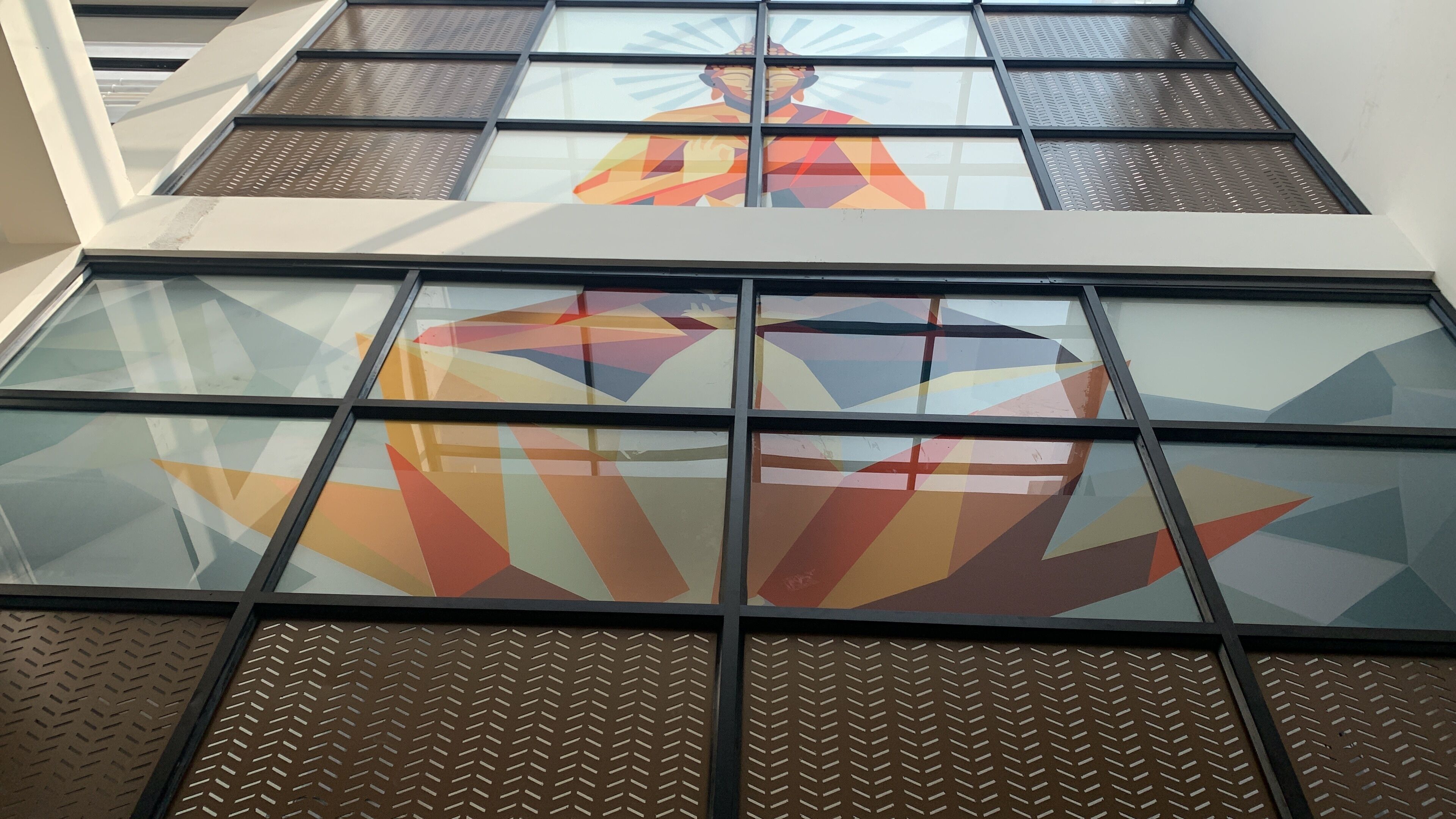 A building facade with large glass windows and metal mesh screens.