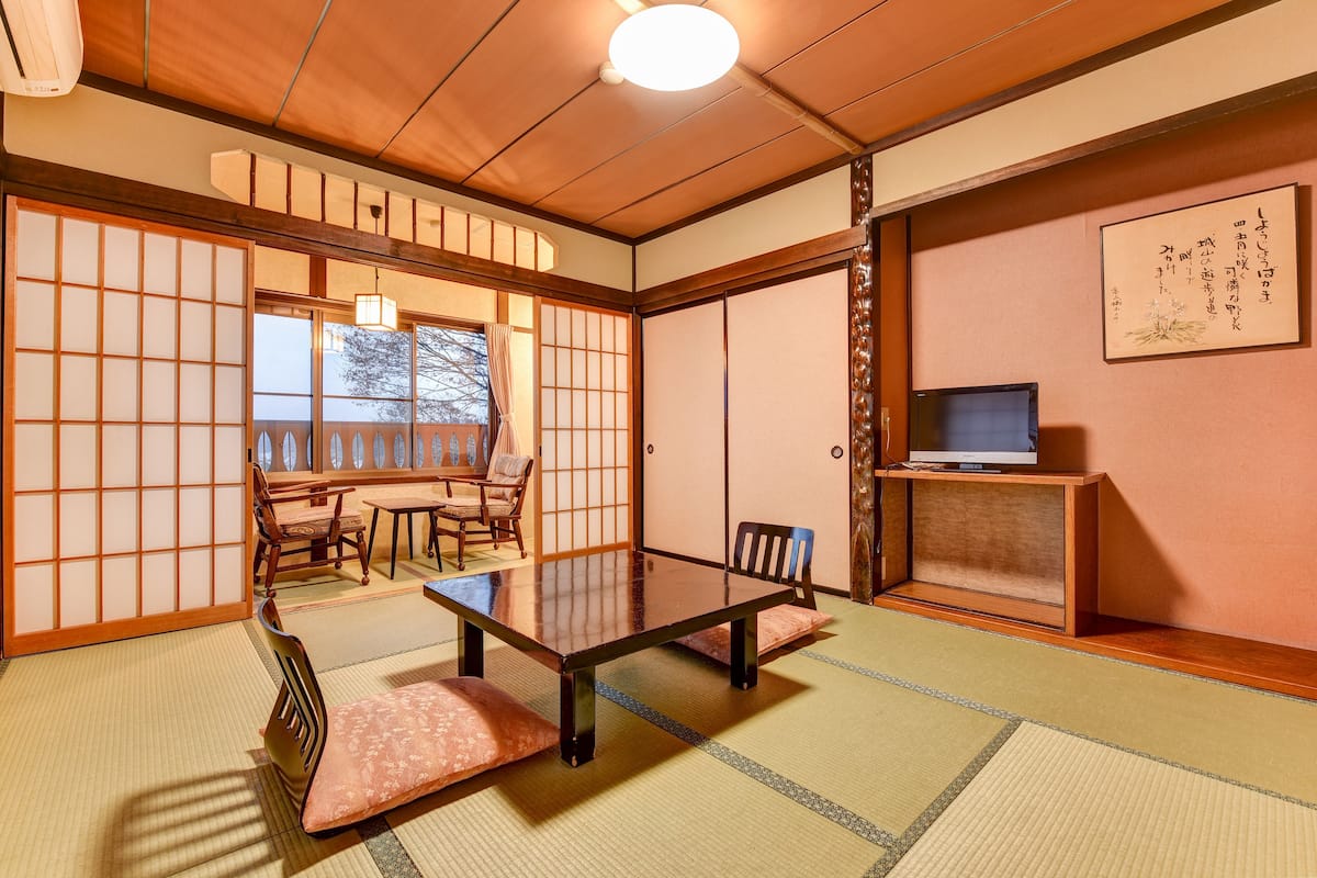 Una habitación japonesa tradicional con suelo de tatami, una mesa baja y puertas correderas.