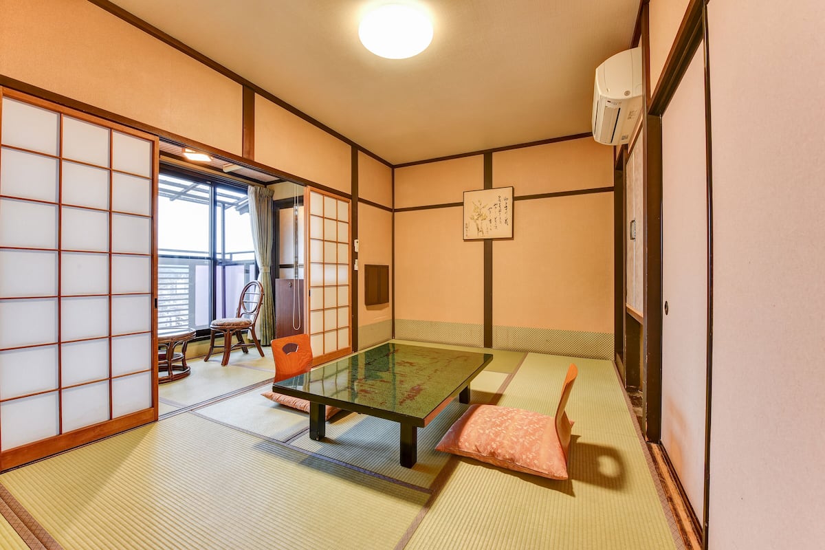 Una habitación japonesa tradicional con suelo de tatami, una mesa baja y puertas correderas.