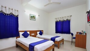Une chambre d’hôtel avec deux lits simples, un bureau et une chaise.