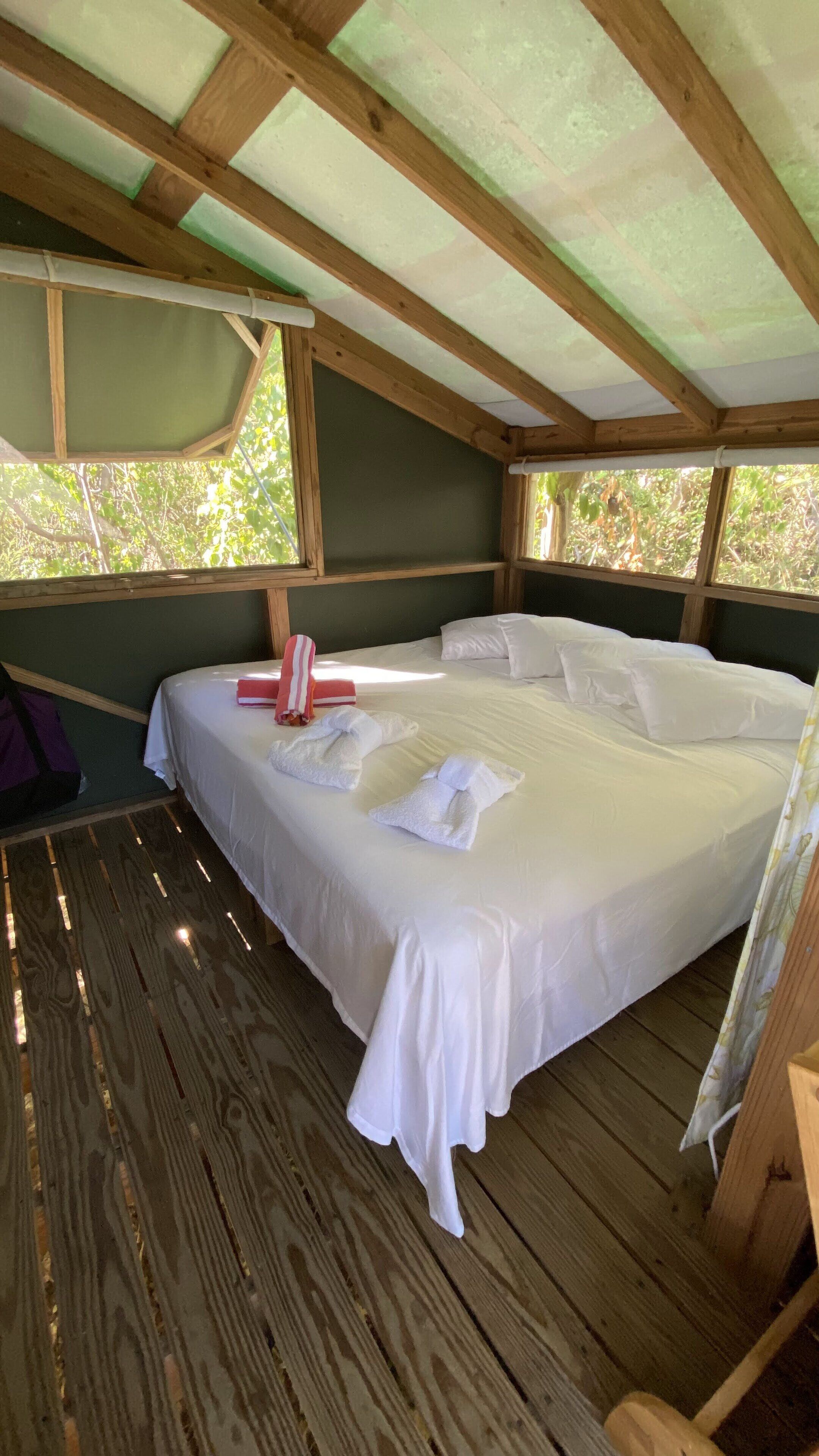Ein Zimmer mit Holzrahmen, einem Bett, weißer Bettwäsche und Handtüchern.