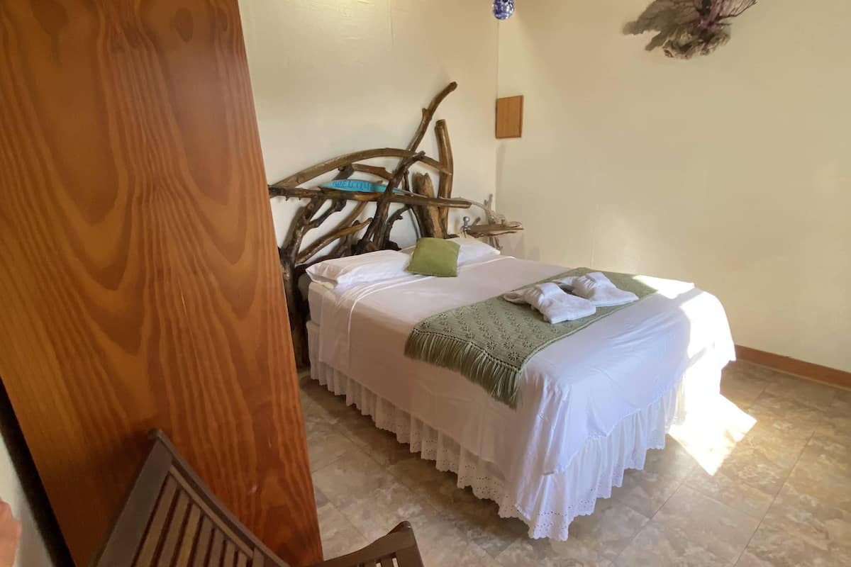 A bedroom with a bed, a wooden headboard, a bench, and a ceiling fan.