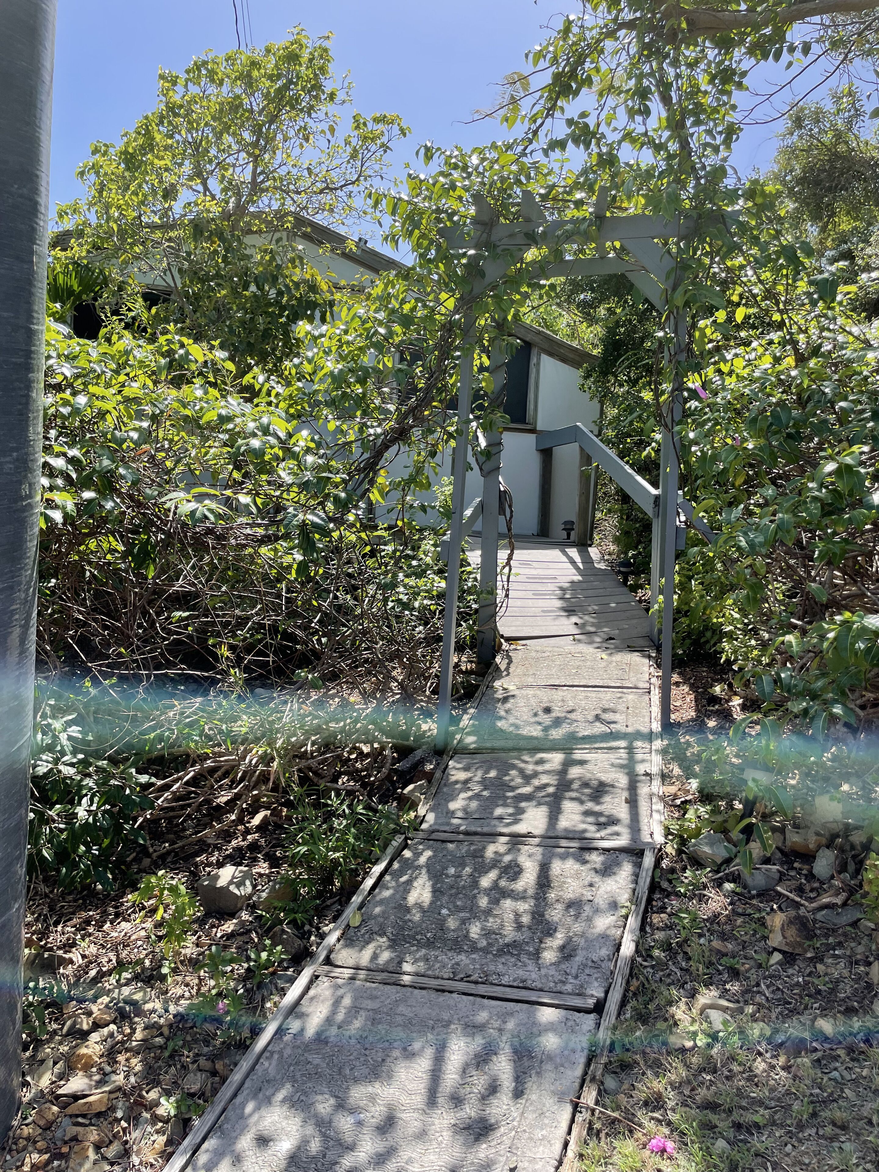 A pathway leading to a house with a pergola structure.