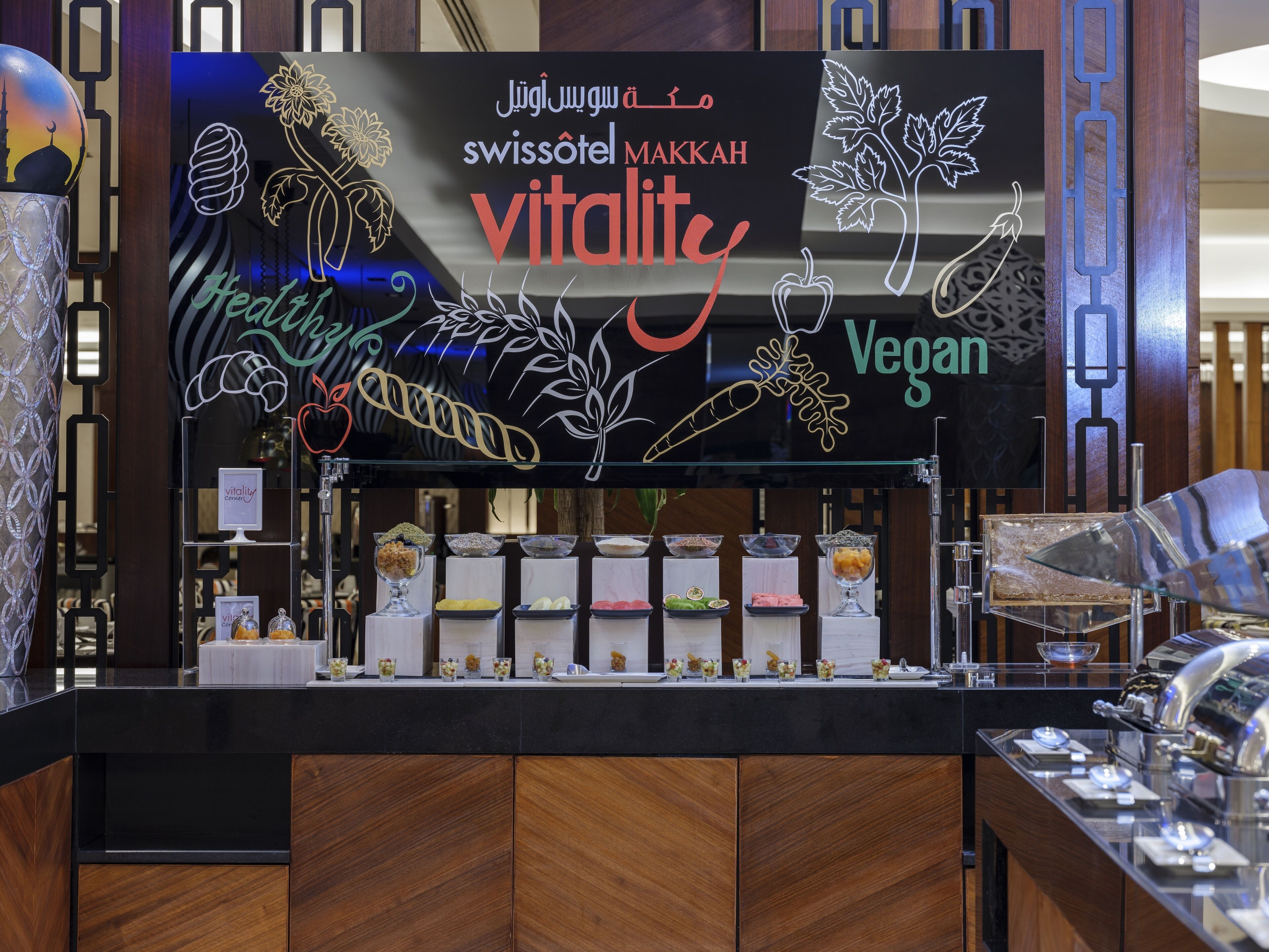 A hotel reception area with a counter displaying various food items and a sign indicating it is a vegan hotel.