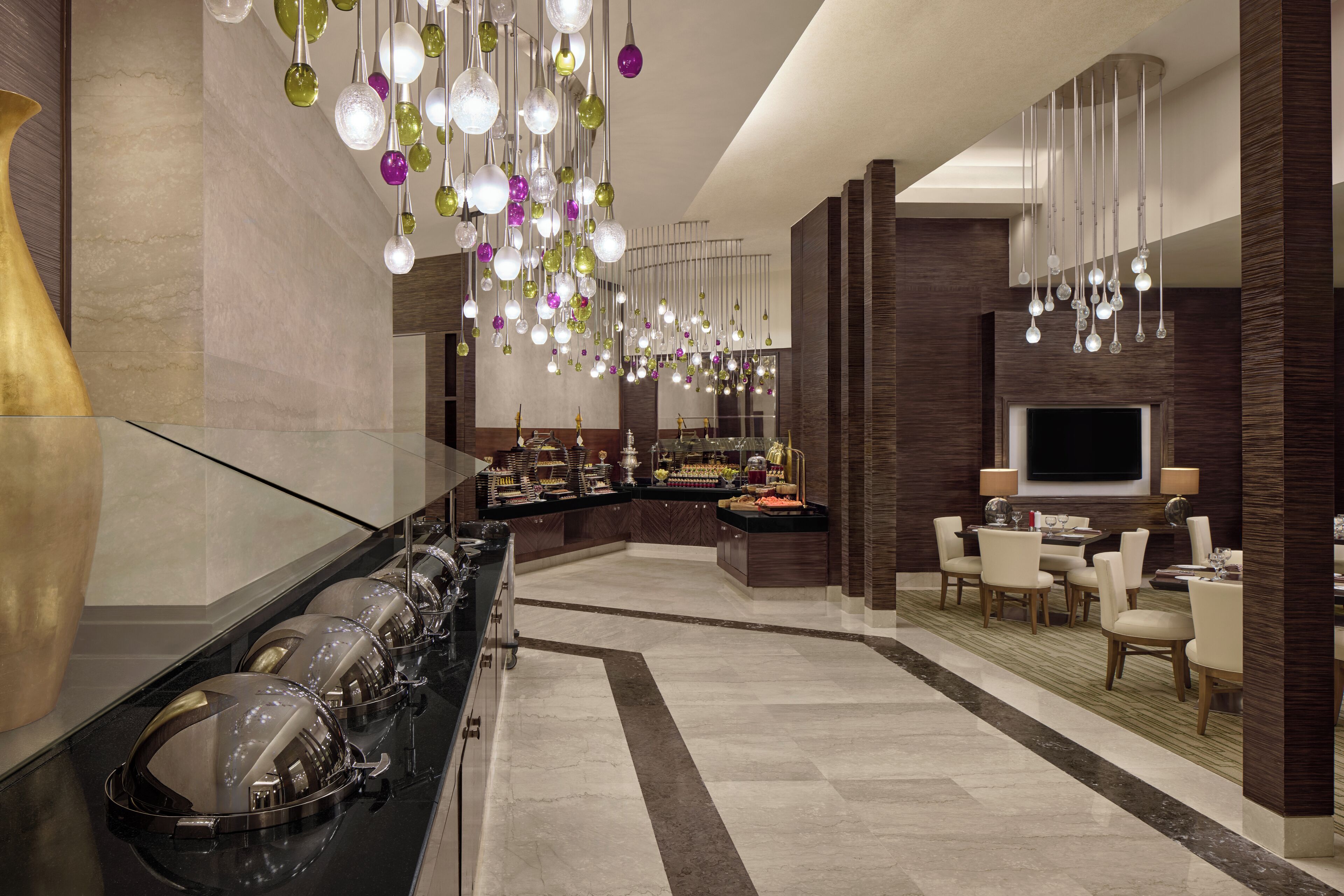 Een moderne hotel lobby met een buffet, een televisie en een zithoek.