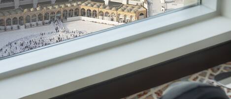 Vista del patio de una mezquita a través de una ventana, con una persona leyendo un libro.