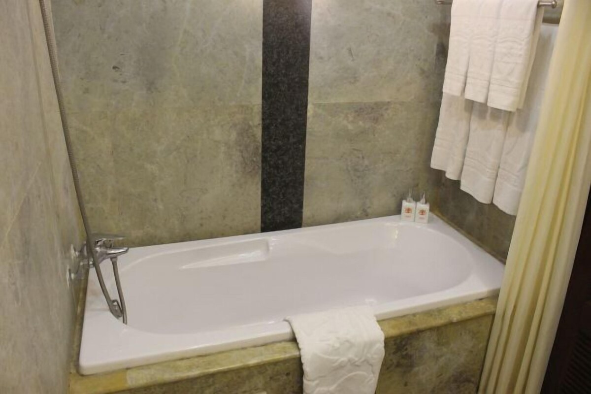Une salle de bain avec une baignoire, un porte-serviettes et un rideau de douche.