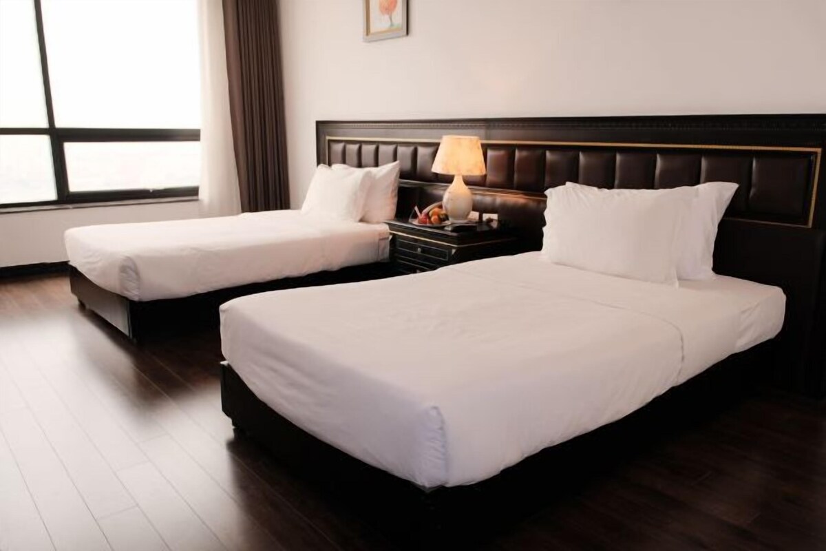 Deux lits simples avec du linge de lit blanc dans une chambre d’hôtel.