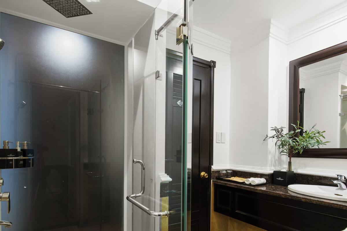 Een moderne badkamer met een douchecabine van glas, een grote spiegel en een vloer betegeld met marmer.