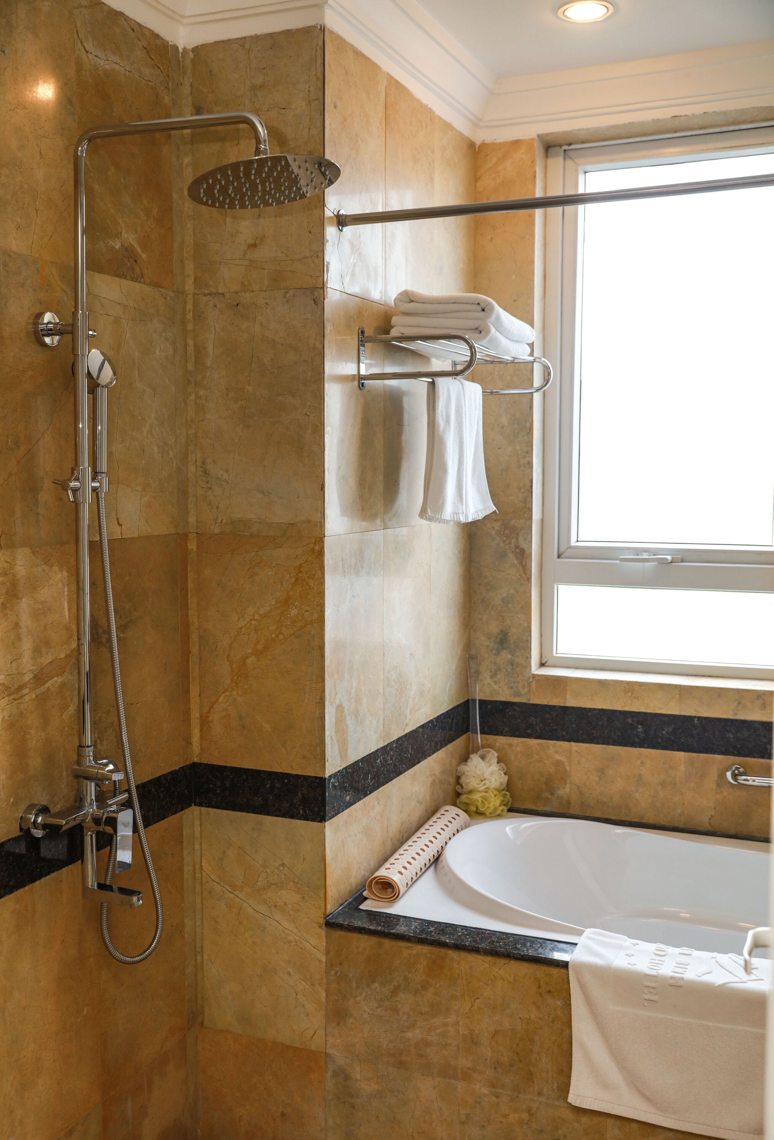 A bathroom with a shower, a bathtub, and a window.