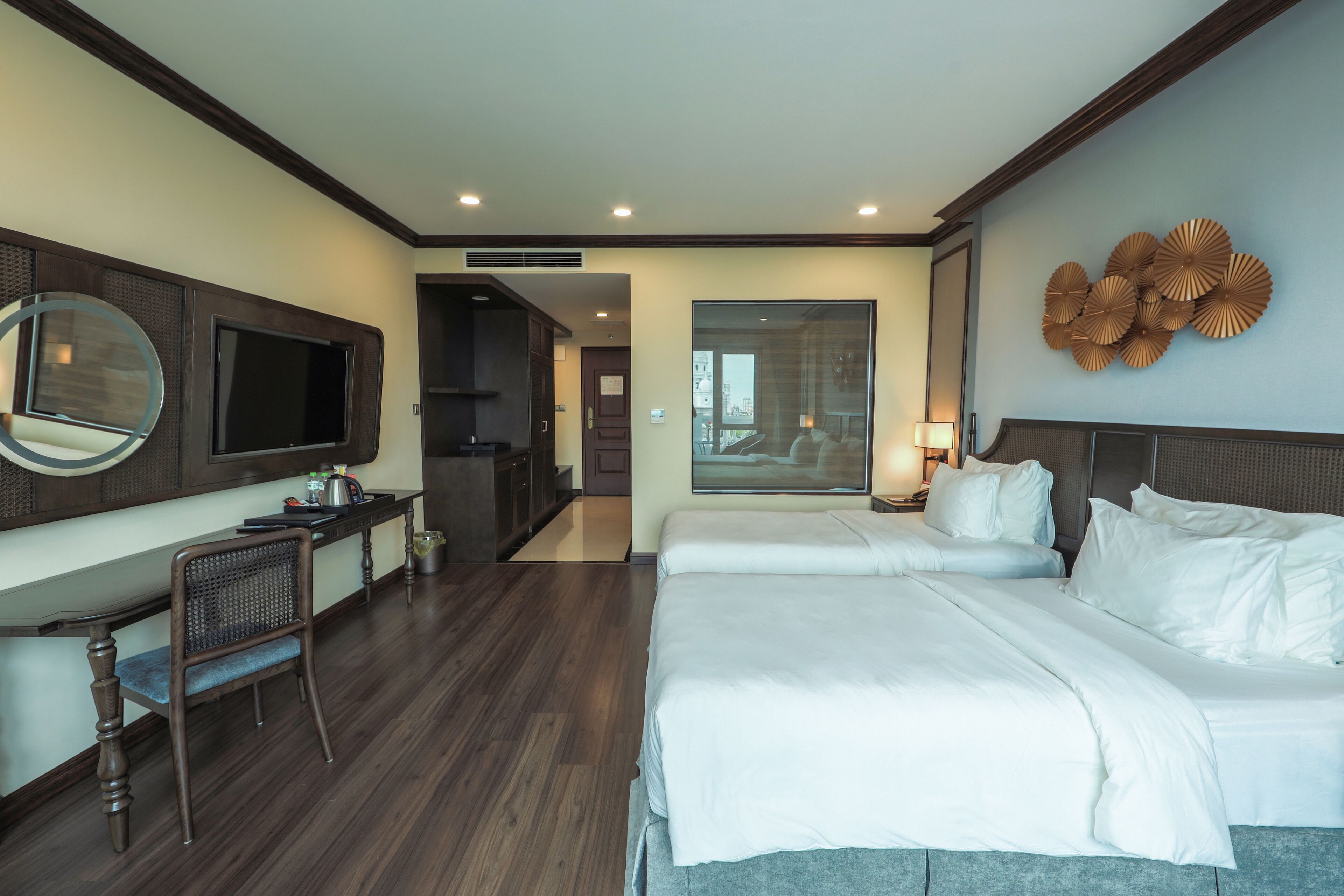 Una habitación de hotel con una cama grande, un escritorio con silla, televisión y un elemento decorativo en la pared.