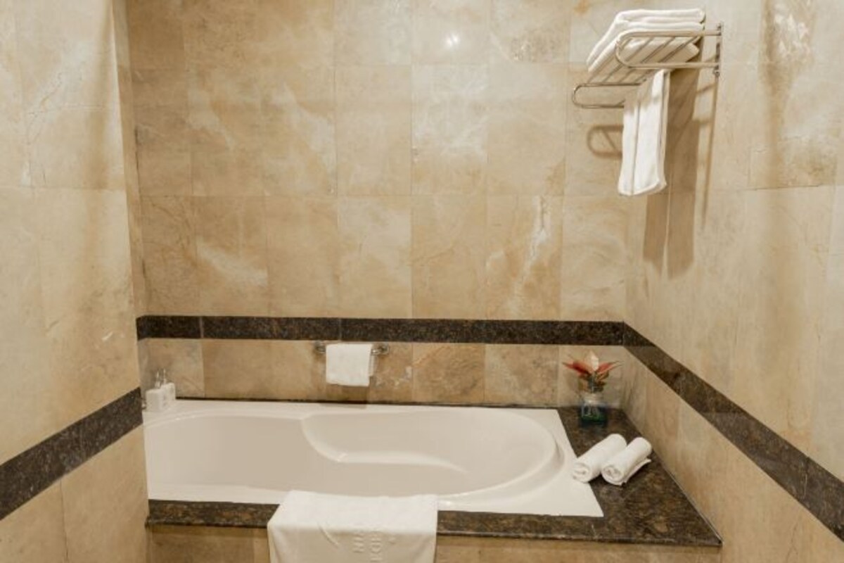 A bathroom with a freestanding bathtub, a towel rack, and a small plant on the counter.