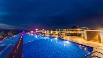 Una piscina al aire libre, sombrillas, sillones reclinables de piscina