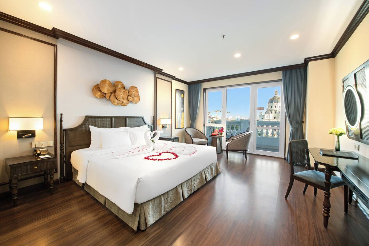 Een hotelkamer met een groot bed, een bureau, een stoel en een uitzicht op een stadsgezicht door het raam.