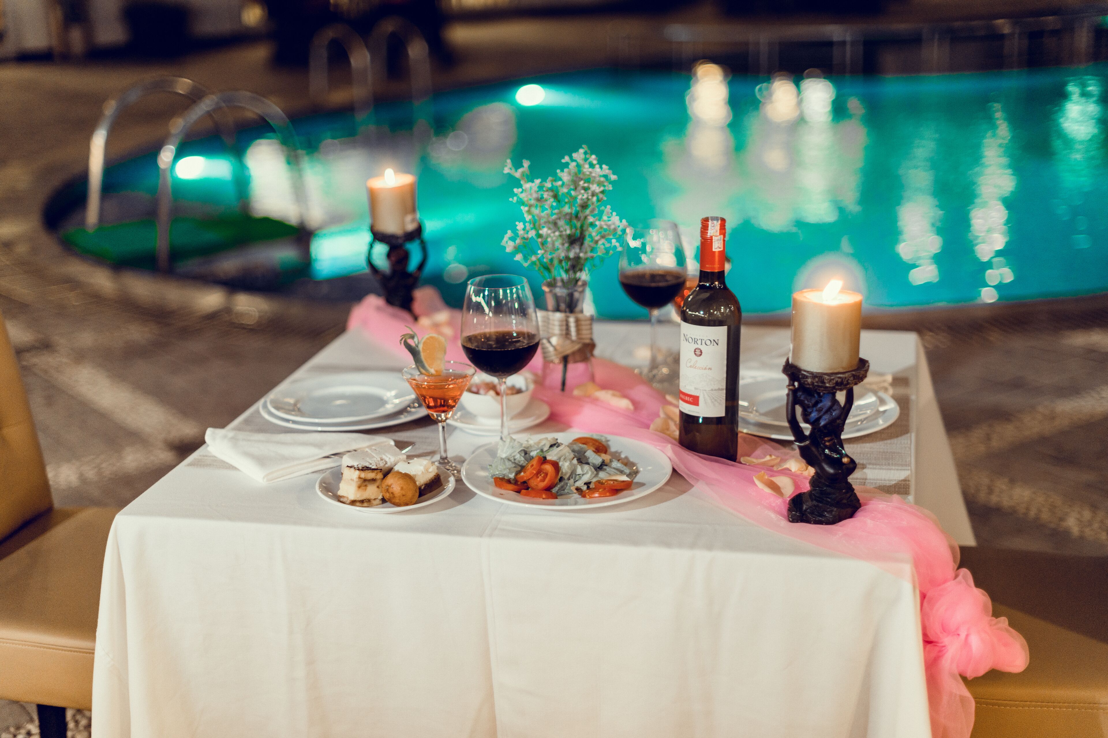 A table set for a meal with a pool in the background.